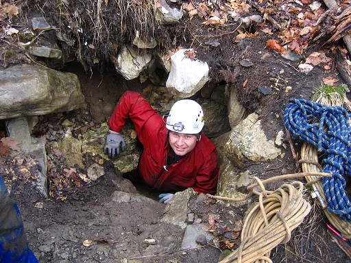 Picture of a caver in a very small cave entrance.